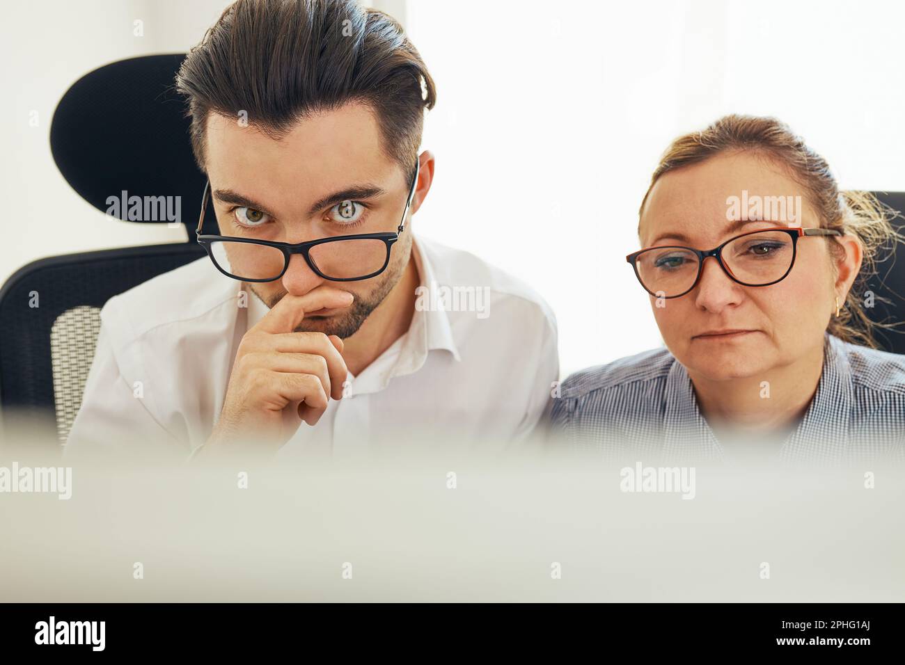 Two business people discussing financial data looking at computer screen. Entrepreneurs working hard sitting at computere screen in office. People hav Stock Photo
