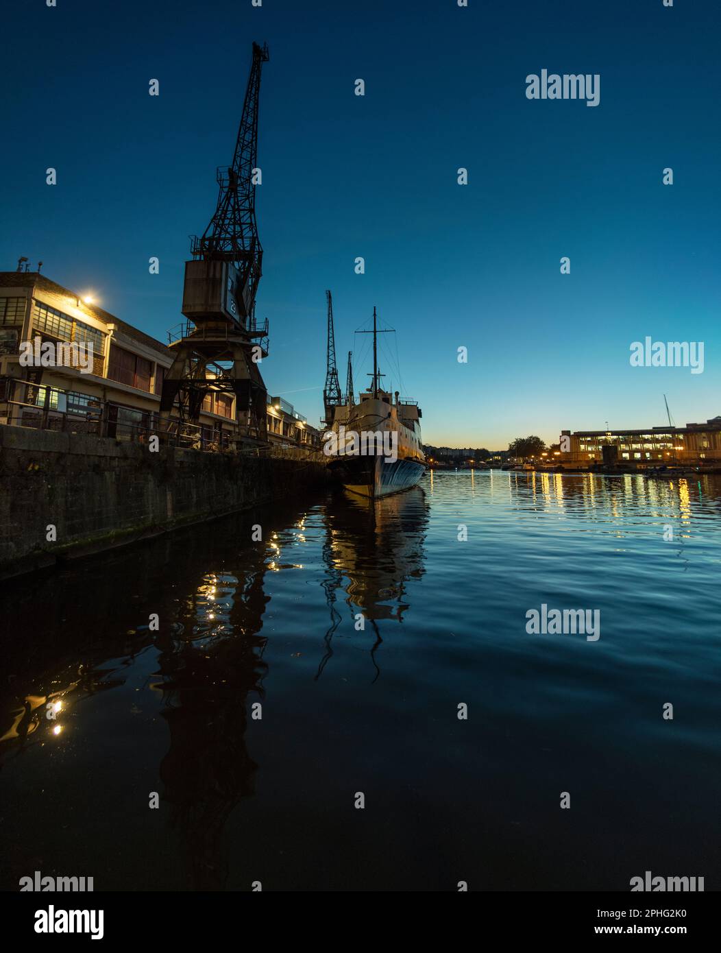 The MV Balmoral ship on Princes Wharf in Bristol a little after sunset, with the lights of the dock and city reflected in the water. Stock Photo