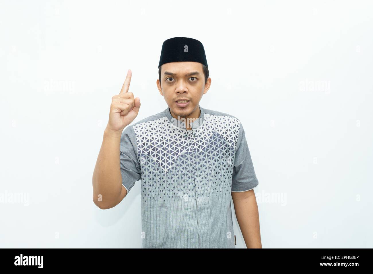 Portrait of Indonesian Asian Muslim man showing finger up, speaking, giving warning gesture Stock Photo