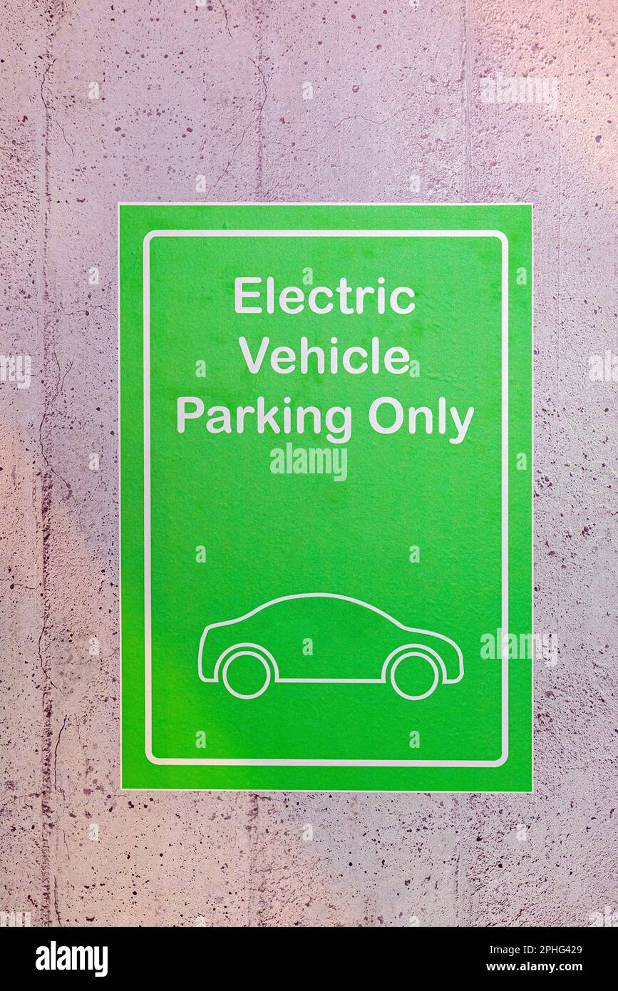 Green Sign Electric Vehicle Parking Only at Concrete Wall Stock Photo