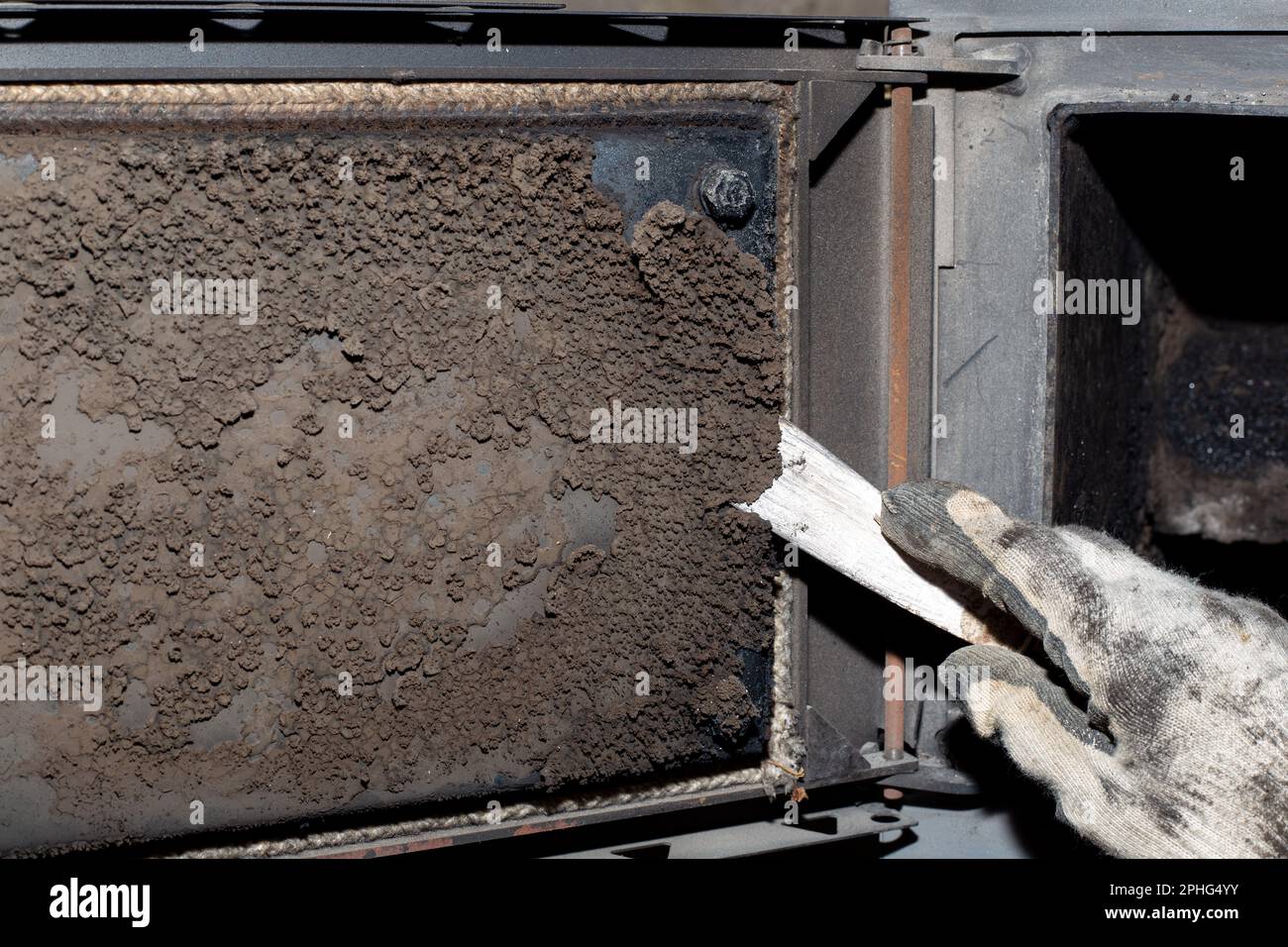 A man cleans a solid fuel boiler from soot and soot. Maintenance of ...