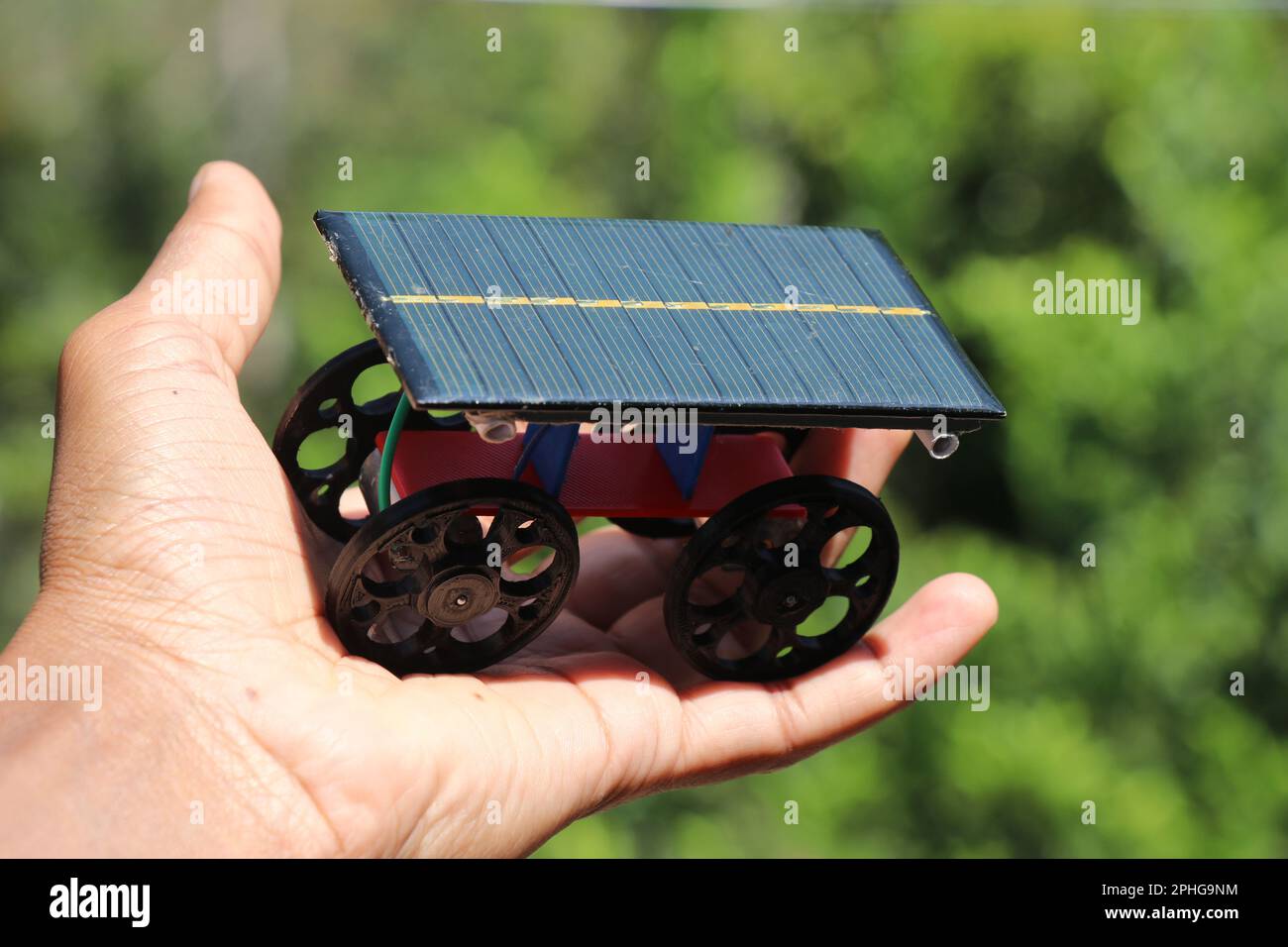Solar powered car made from photovoltaic cell and 3D printed wheels powered by a small dc motor held in hand Stock Photo