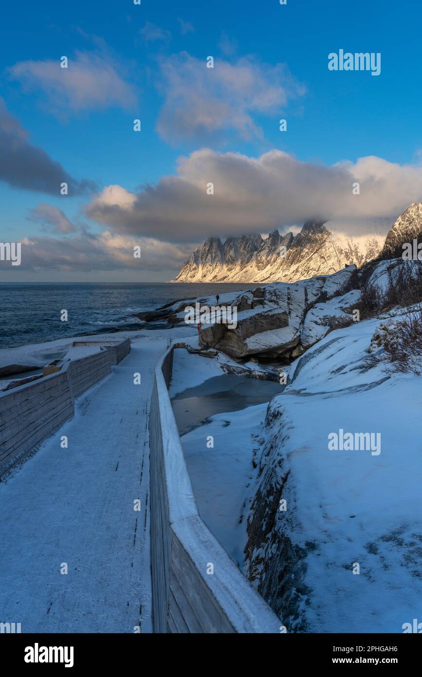am Fels sich brechende Wellen des Atlantik bei Tungeneset, Senja, Norwegen, mit den steilen Bergen Okshornan im Hintergrund. stürmisches Winterwetter Stock Photo