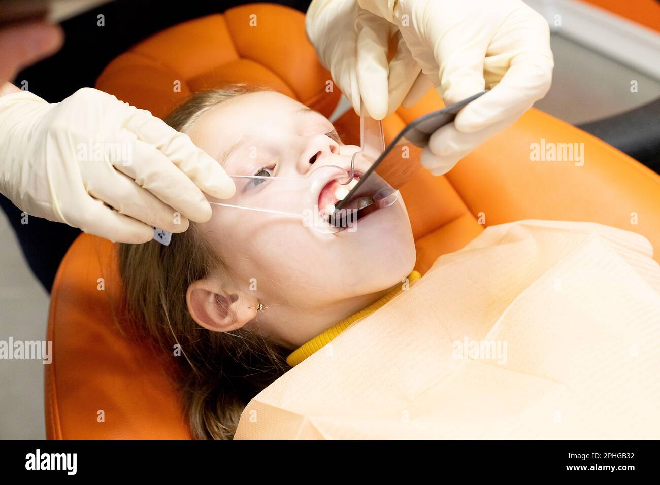 male dentist bent over a child looks at her jaw. Child during