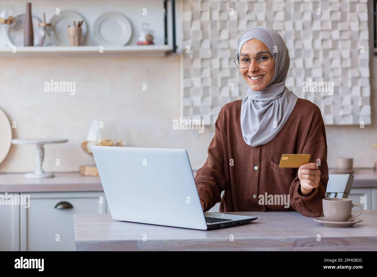 Portrait of young muslim business woman in hijab sitting at home at ...