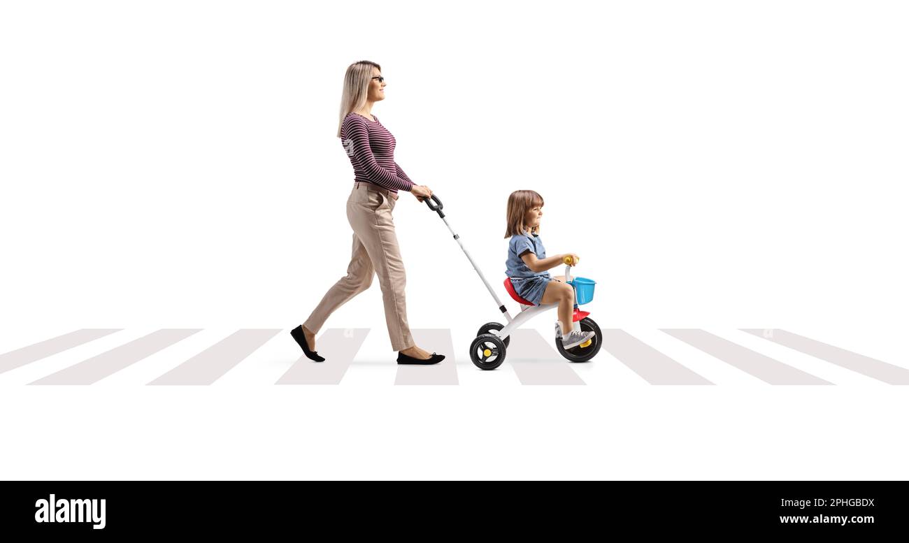 Mother pushing a child on a tricycle at a pedestrian crossing isolated on white background Stock Photo