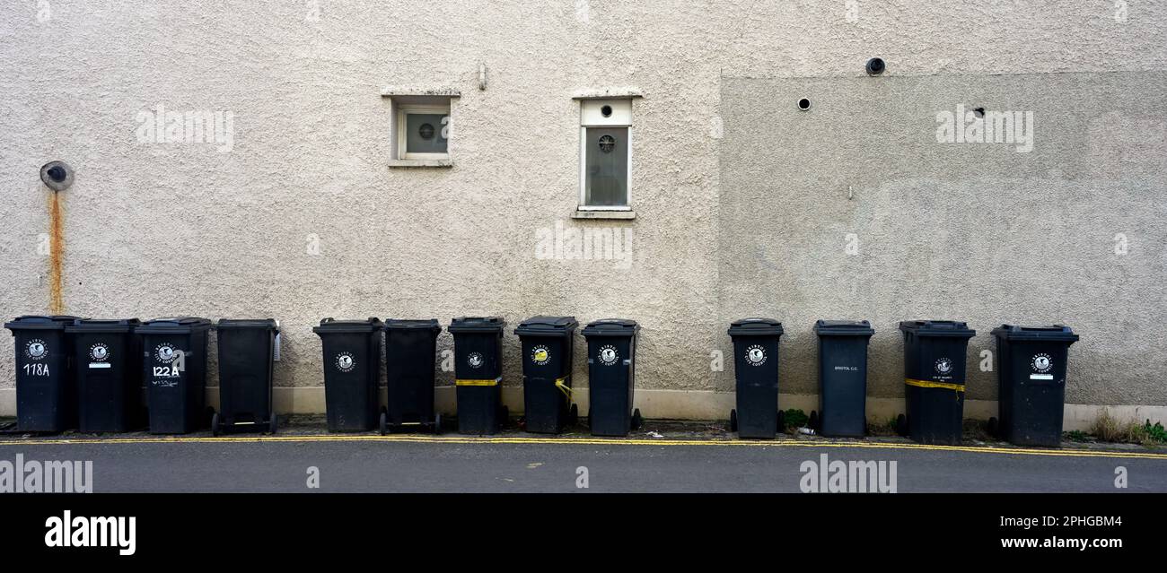 Long row (13) of black domestic rubbish bins out for collection along