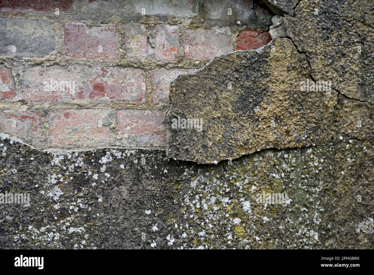 Brick wall rendered with a hard cement which is cracking and falling off Stock Photo
