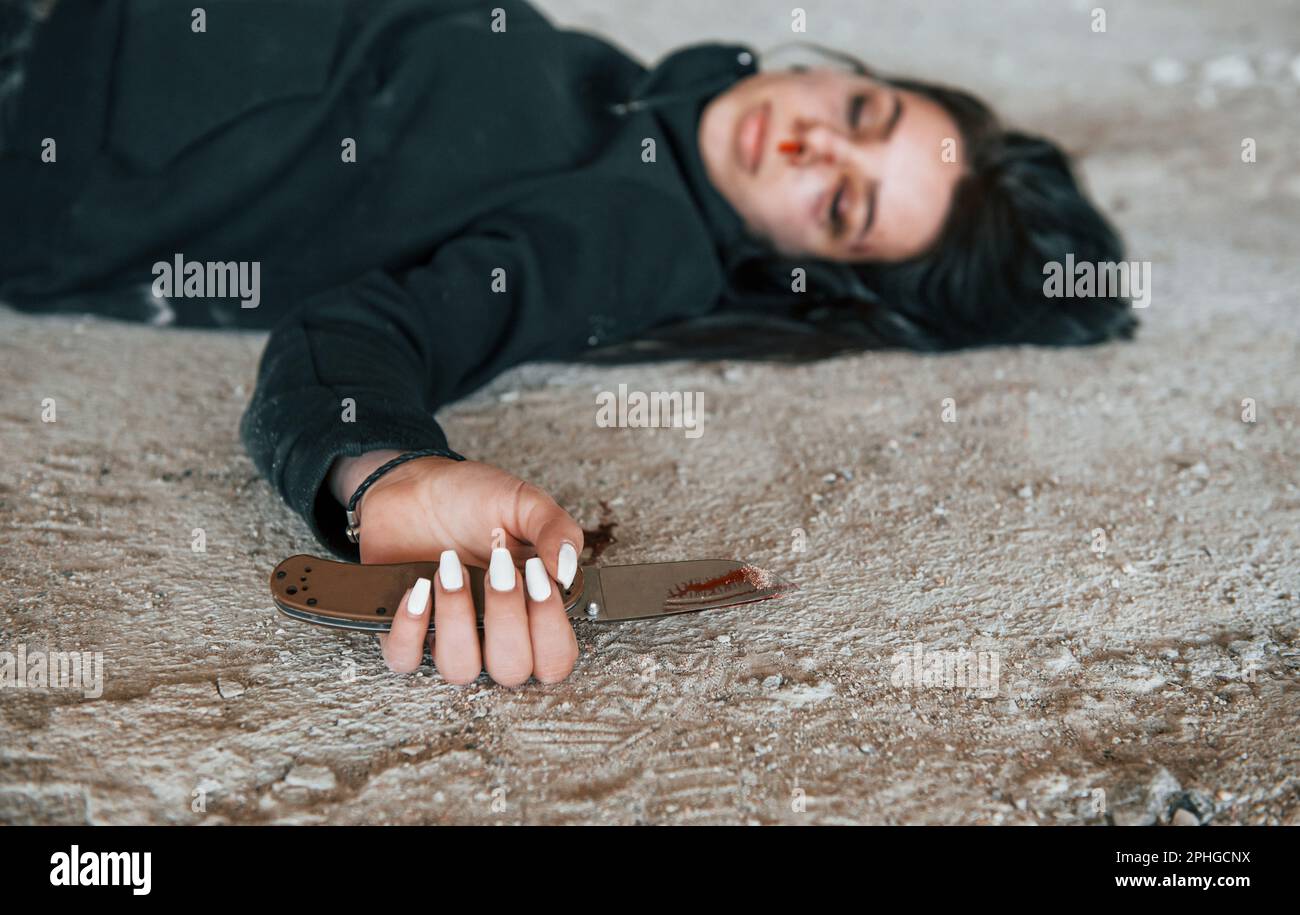 Corpse of female victim of crime lying down on the ground of abandoned building Stock Photo
