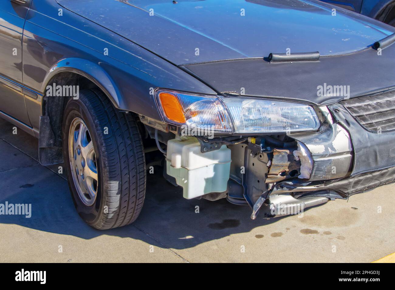 Wrecked car - silver blue sedan showing passenger front that has been in accident with part of bumper missing so you can see inside and how bumper is Stock Photo