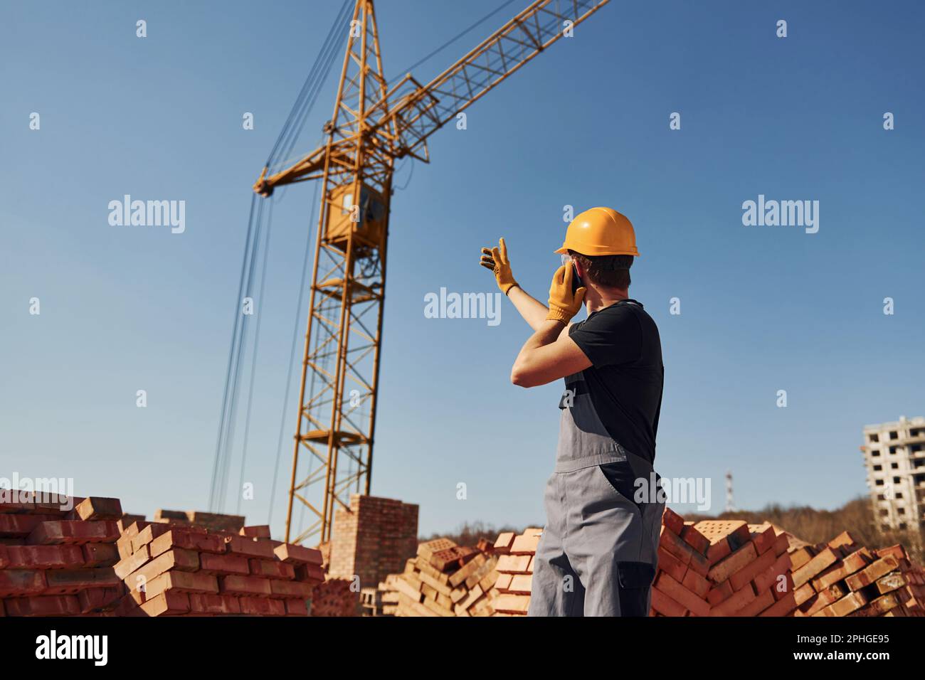 Communicating with crane guy. Construction worker in uniform and safety