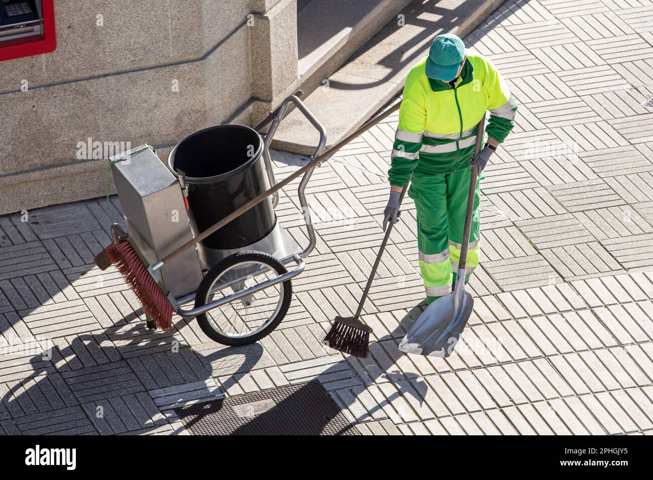 Street sweeper working on a sidewalk with her shovel, cart and broom. Urban cleaning concept Stock Photo