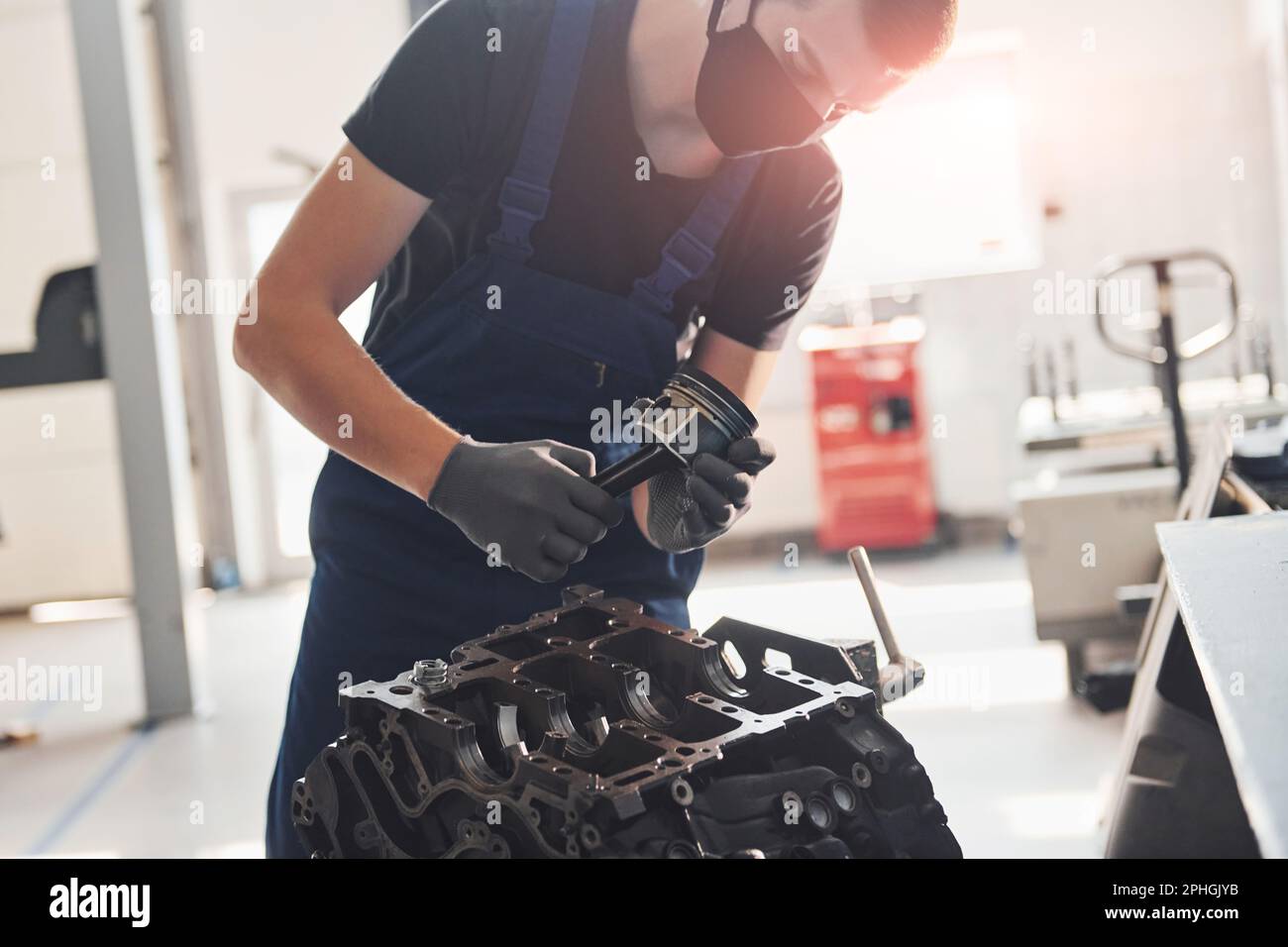 Engine With Mask Professional repairman in black protective mask works with broken ...