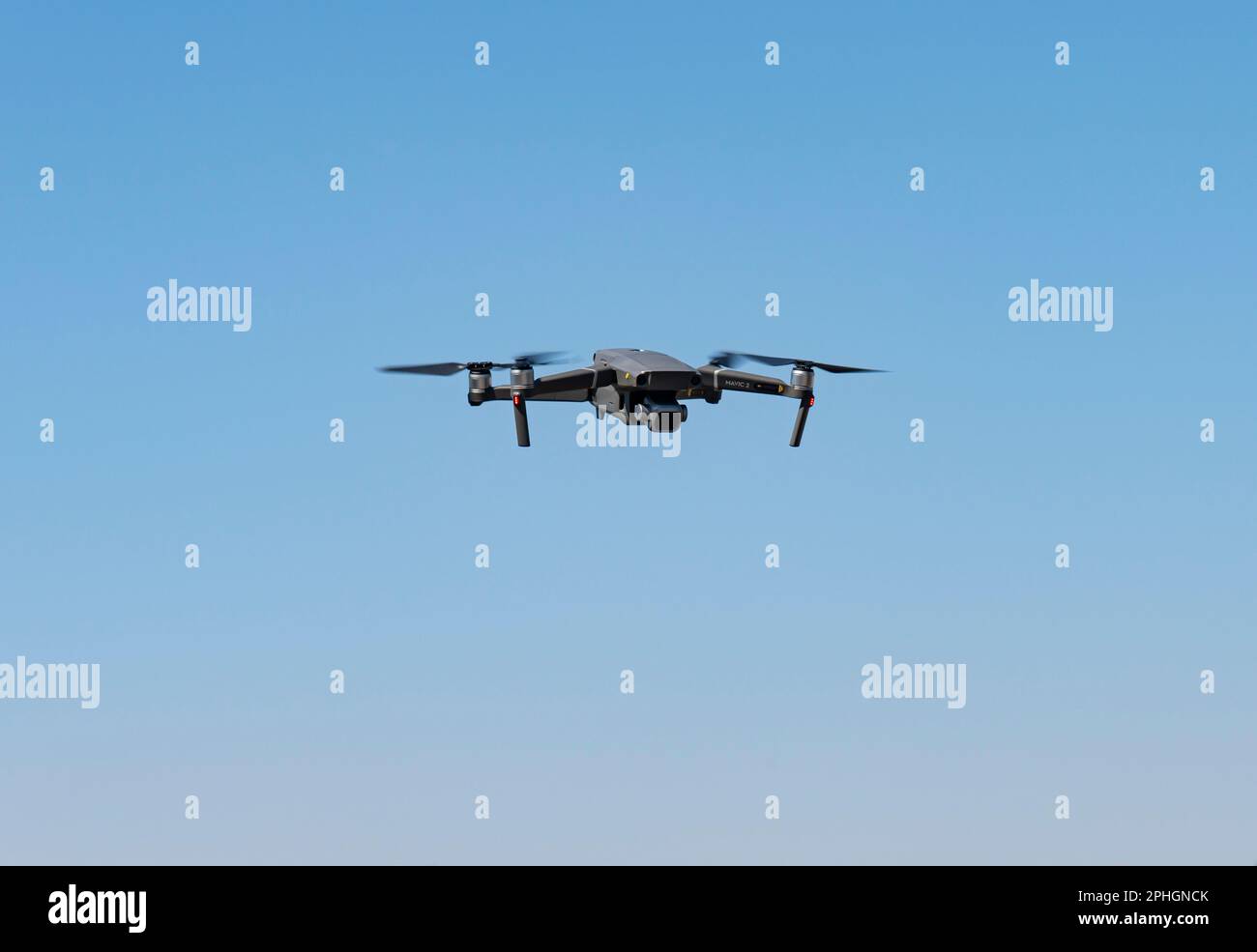 A flying mini drone recording video and photos in the blue sky Stock Photo