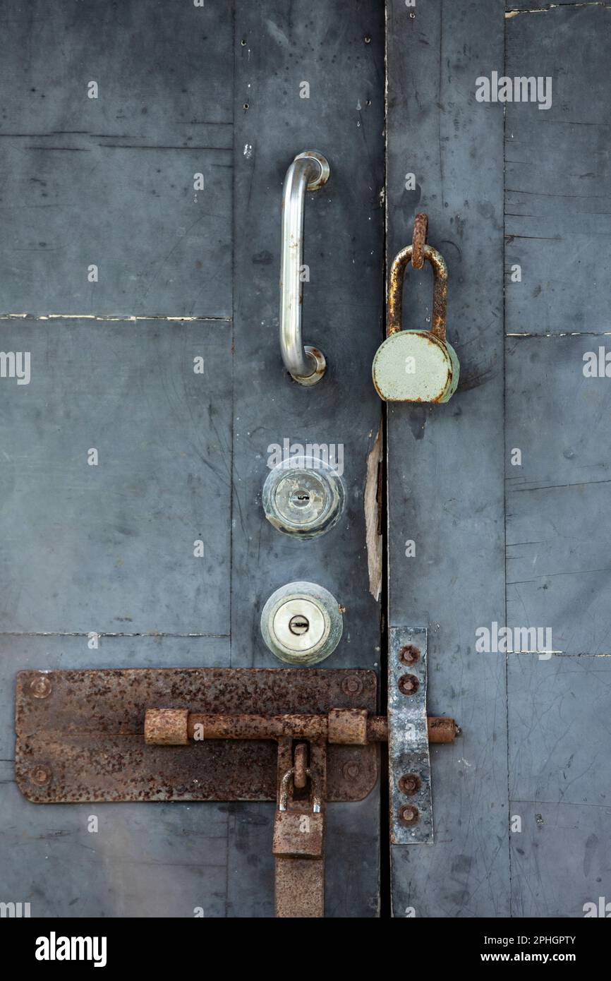 Weathered metal security door covered in locks on the island of Cozumel, Mexico. Stock Photo