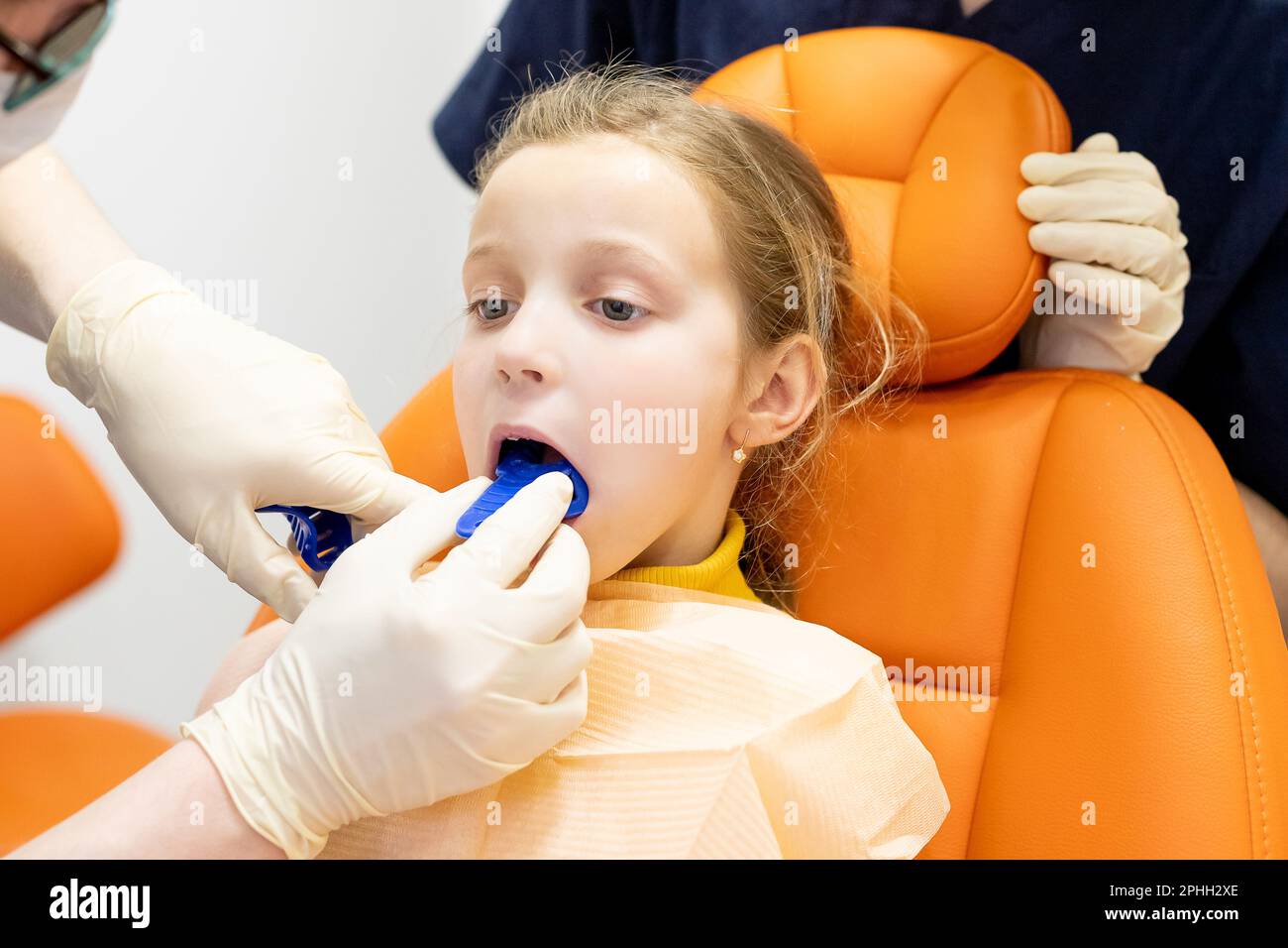The orthodontist demonstrates to the girl patient the impression tray