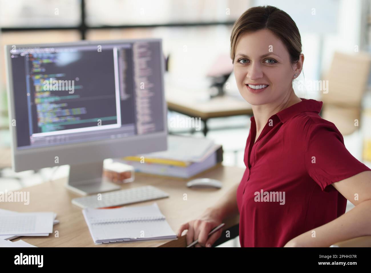 Smiling woman app developer writes code in company office Stock Photo