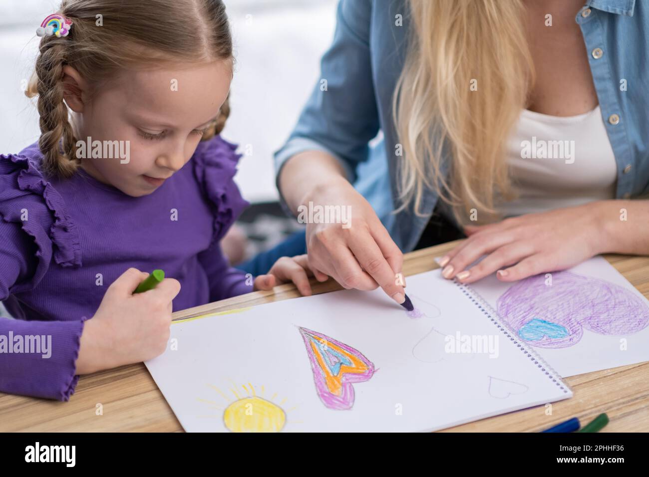 Close up on little girl painting at home with mom using crayon and ...