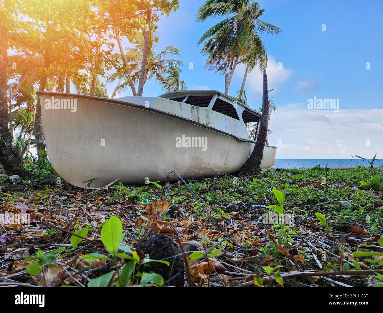 Damaged ship stuck on beach on blue sea and sky background Stock Photo
