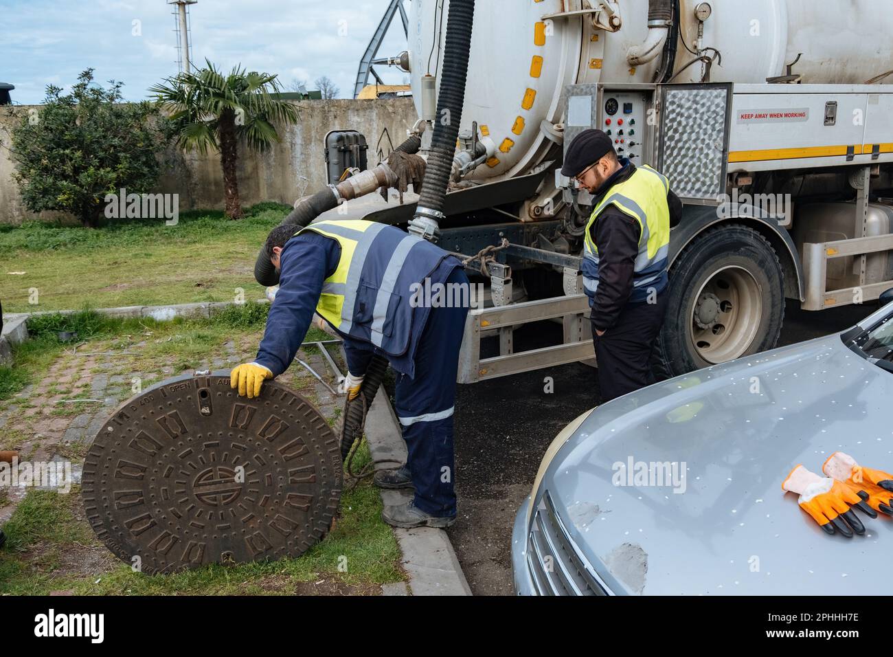 Sewer workers cleaning manhole and unblocking sewers the street sidewalk. Stock Photo