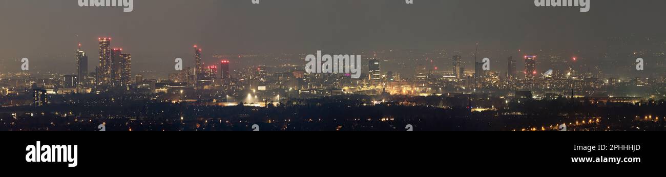 The skyline of Manchester at night, photographed from the edge of the city on Werneth Low, with the towers and city lights glowing in the distance Stock Photo