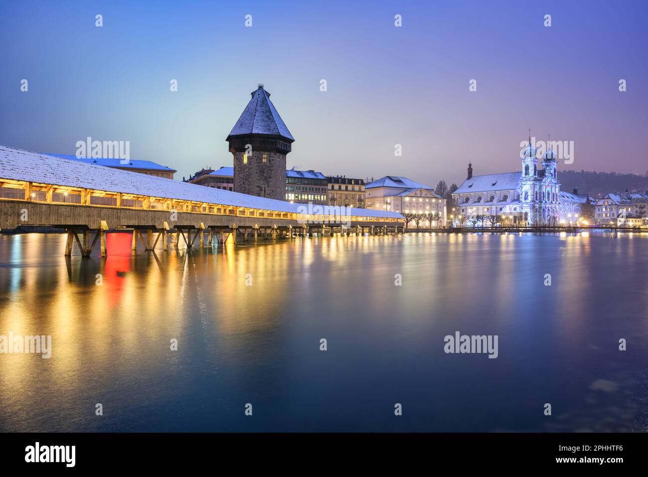 The wooden Chapel bridge, the Water tower and St Francis Jesuit Church reflecting in Reuss river in historical Lucerne Old town, Switzerland, on a win Stock Photo