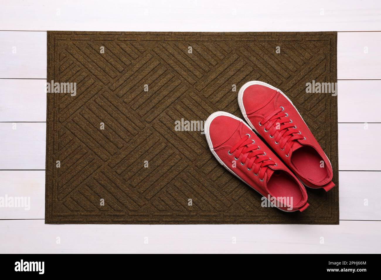 New clean door mat with shoes on white wooden floor, top view Stock