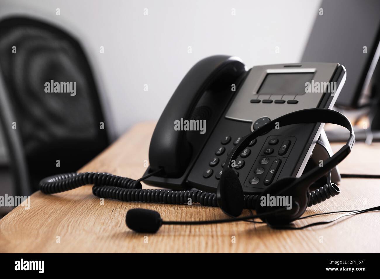 Stationary phone and headset on wooden desk in office. Hotline service