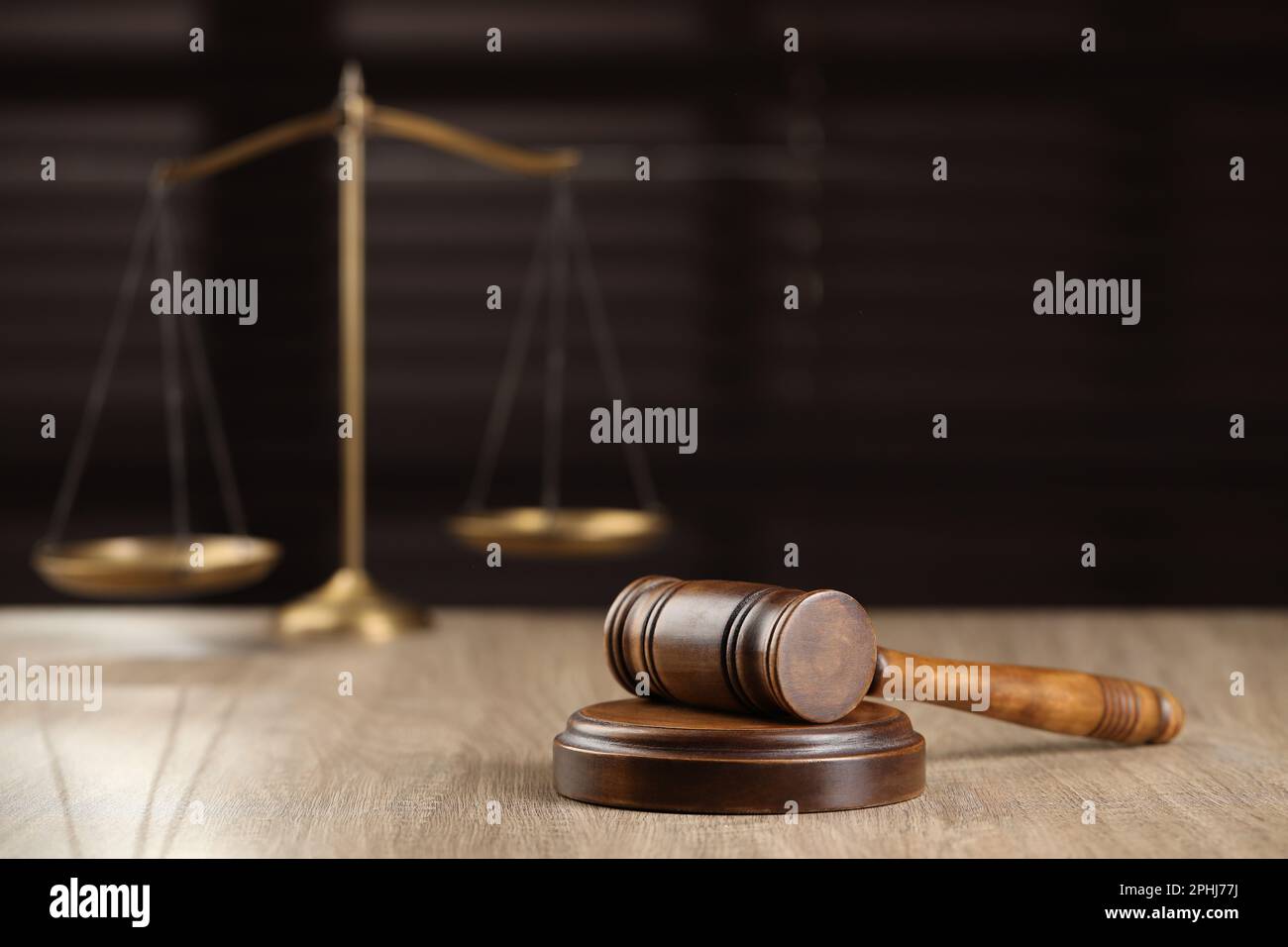 Wooden gavel and scales of justice on table against blurred background ...