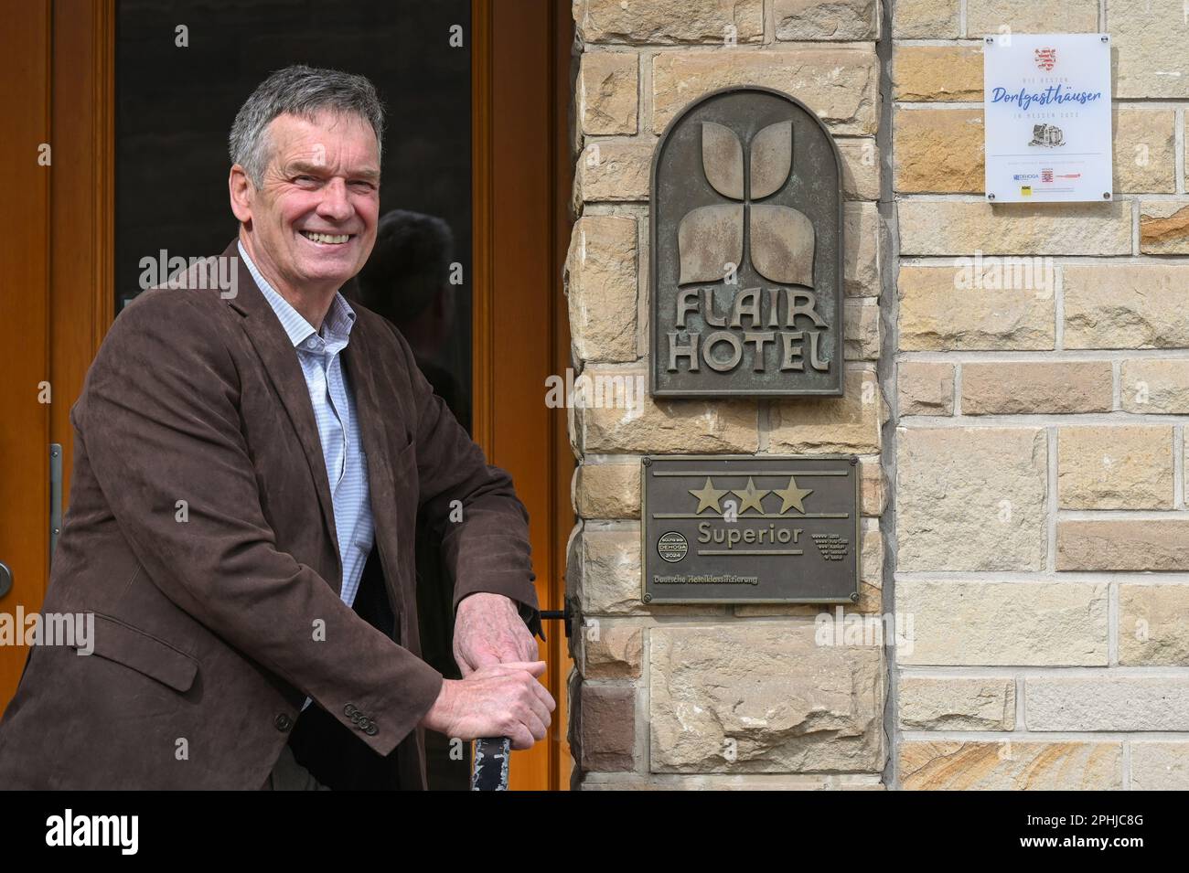 Waldeck, Germany. 22nd Mar, 2023. Christian Gerlach, owner of the Hotel Werbetal in the district of Nieder-Werbe, stands in front of the hotel entrance. Even before the Corona pandemic, the owner and his family equipped the 28 rooms of his hotel with tablets and Internet-enabled TVs. Bookings in the restaurant are thus possible at any time, and there is also a stable WLAN network on the terrace. (to dpa 'Are hotels and restaurants in Hesse being left behind digitally?') Credit: Uwe Zucchi/dpa/Alamy Live News Stock Photo