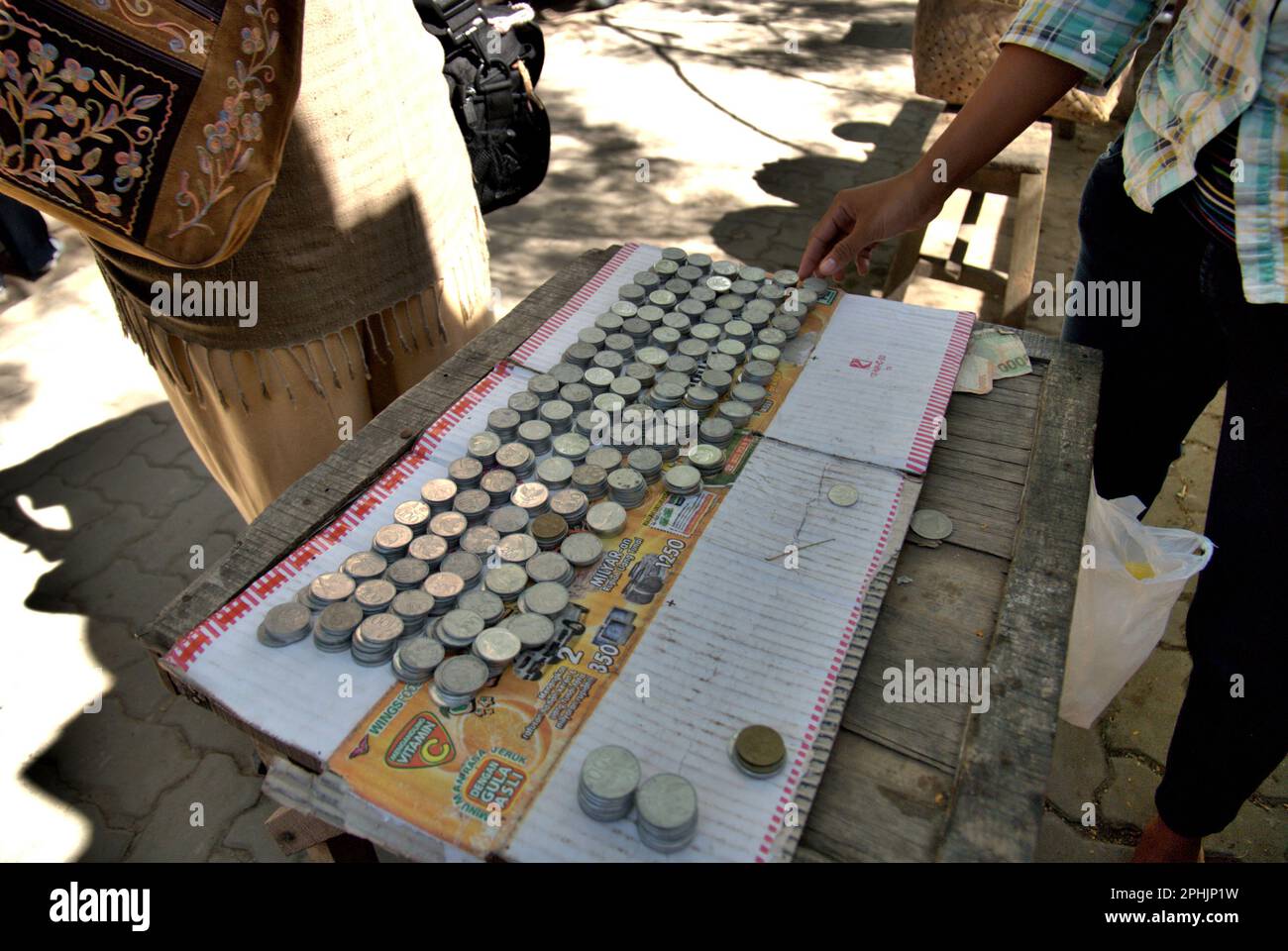 A vendor of coins—a common offering in pilgrimage activity according to local tradition—at the complex of the Great Mosque of Banten, a cultural heritage from Banten Sultanate period located in an area now called Banten Lama (Old Banten) in Serang, Banten, Indonesia, on this photo taken in 2010. 'The sustainability of cultural heritage is strongly linked to the effective participation of local communities in the conservation and management of these resources,' according to a team of scientists led by Sunday Oladipo Oladeji in their research article published on Sage Journals in October 2022. Stock Photo