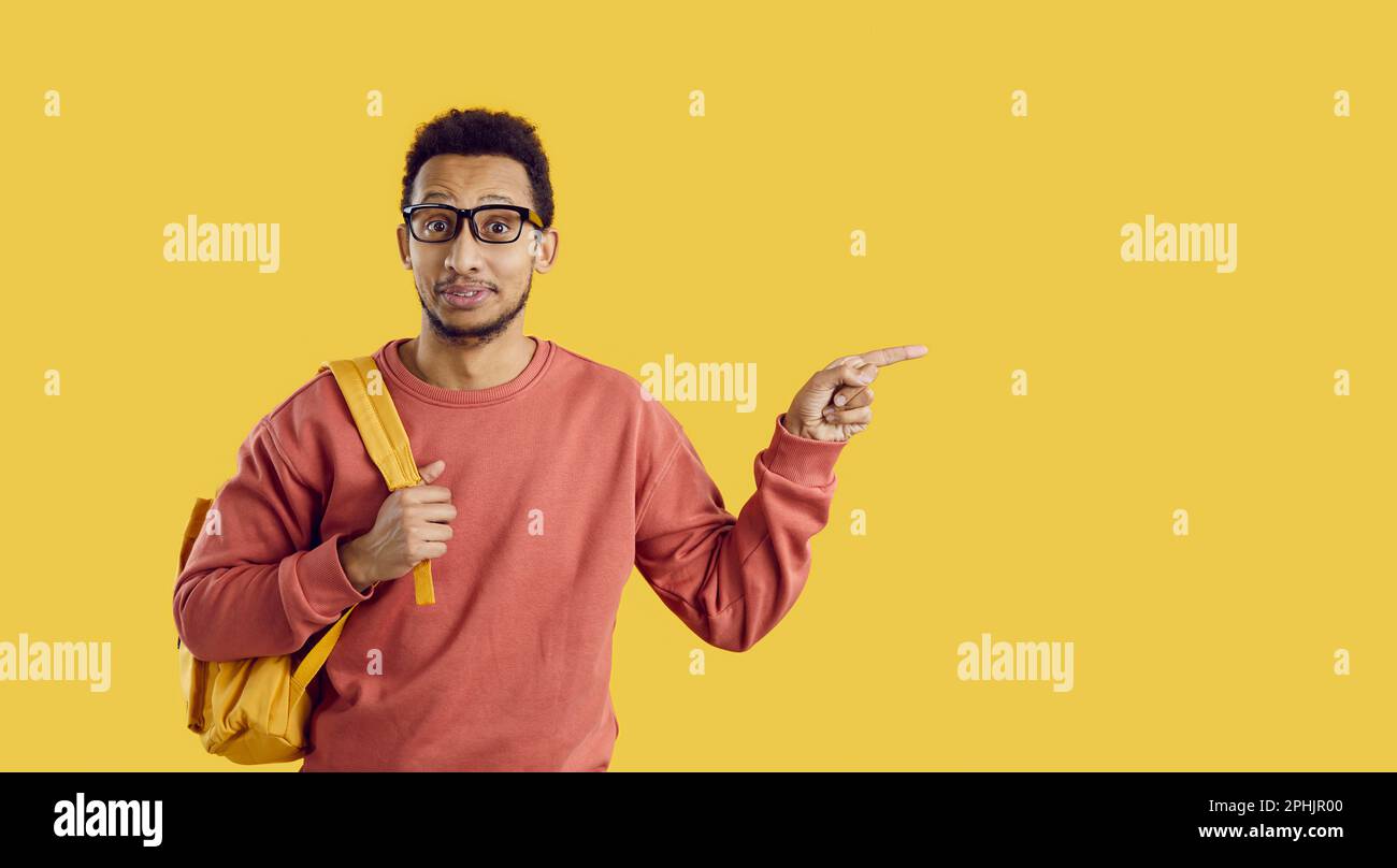 Happy college or university student pointing to the side on copy space background Stock Photo