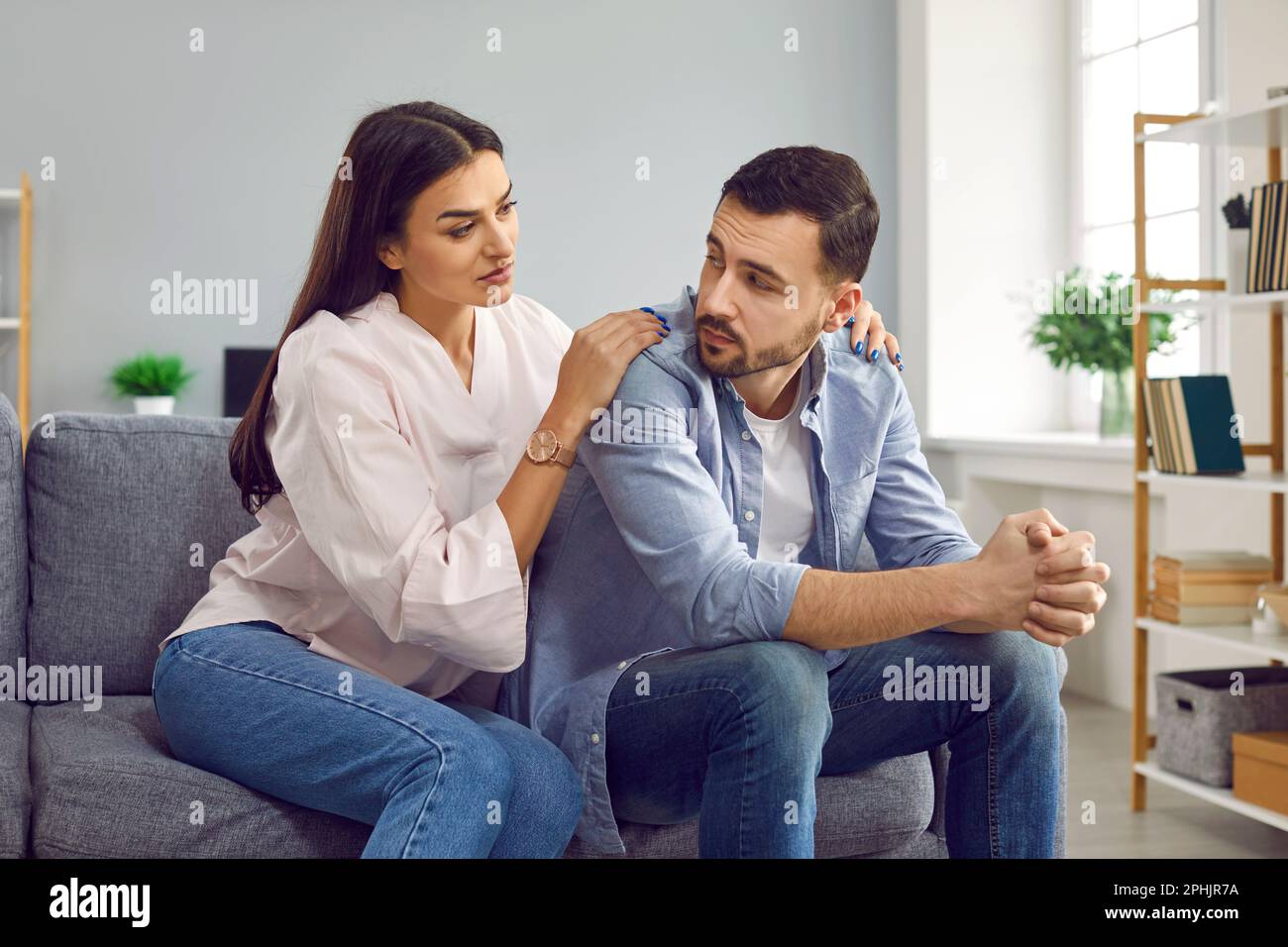 Attractive wife hugging husband from back to comfort or apologize Stock Photo