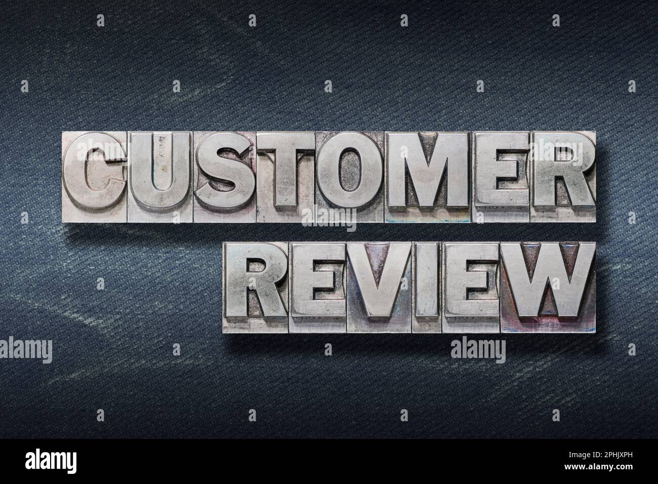 customer review phrase made from metallic letterpress on dark jeans background Stock Photo