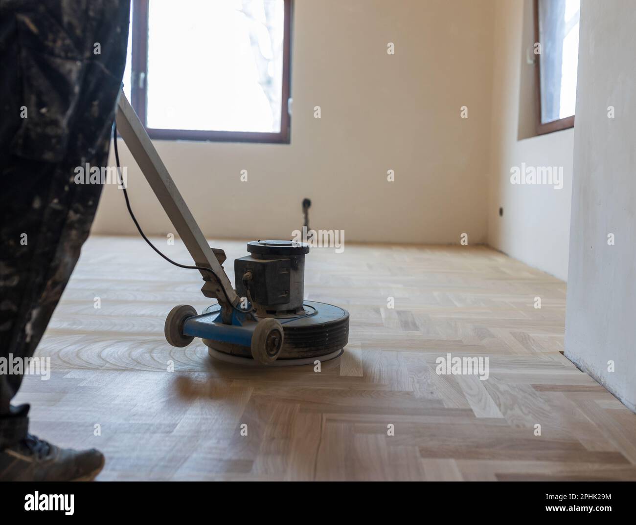 Craftsman polishing parquet floor with machine. Home renovation concept