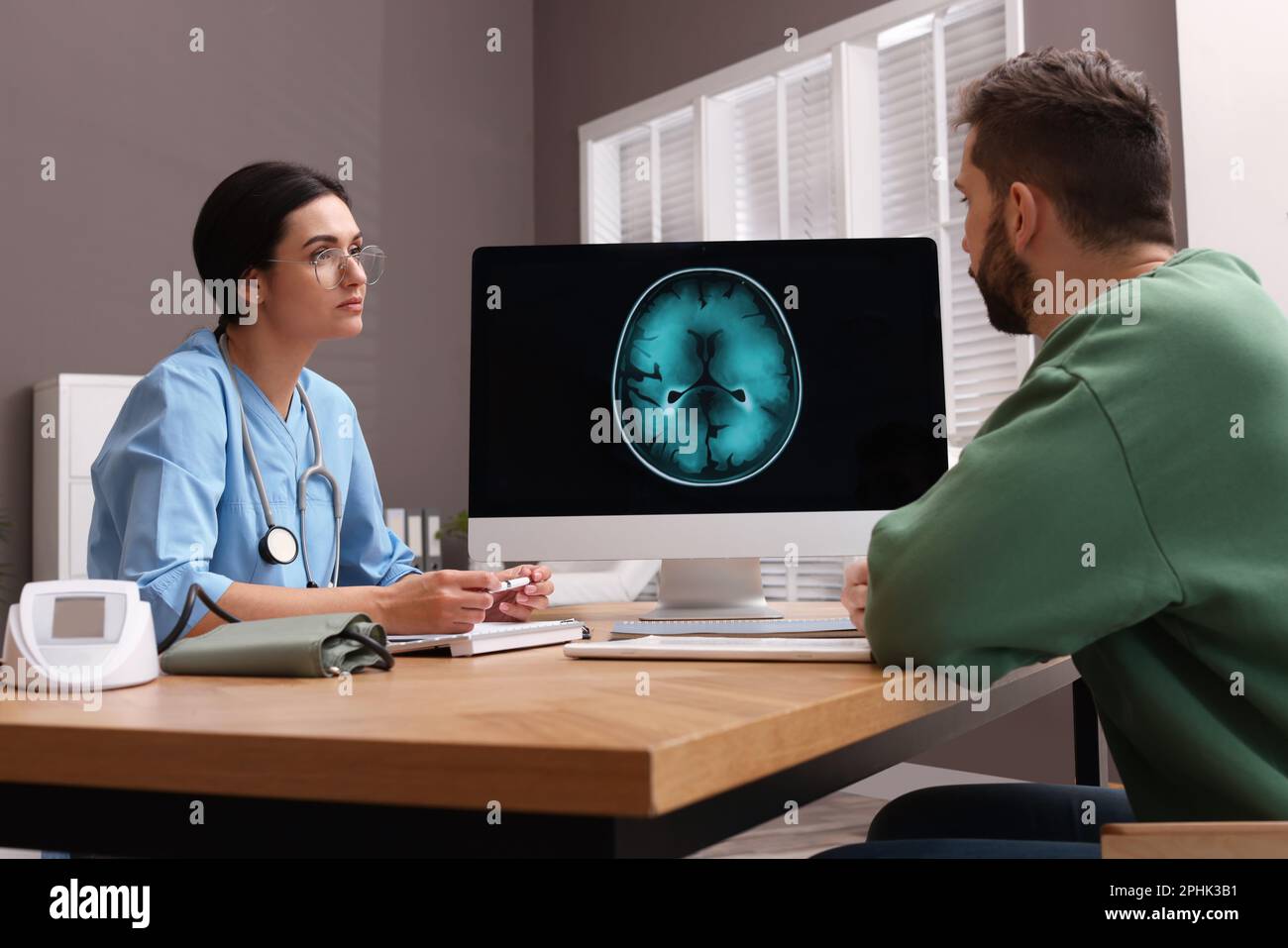 Neurologist consulting patient at table in clinic Stock Photo