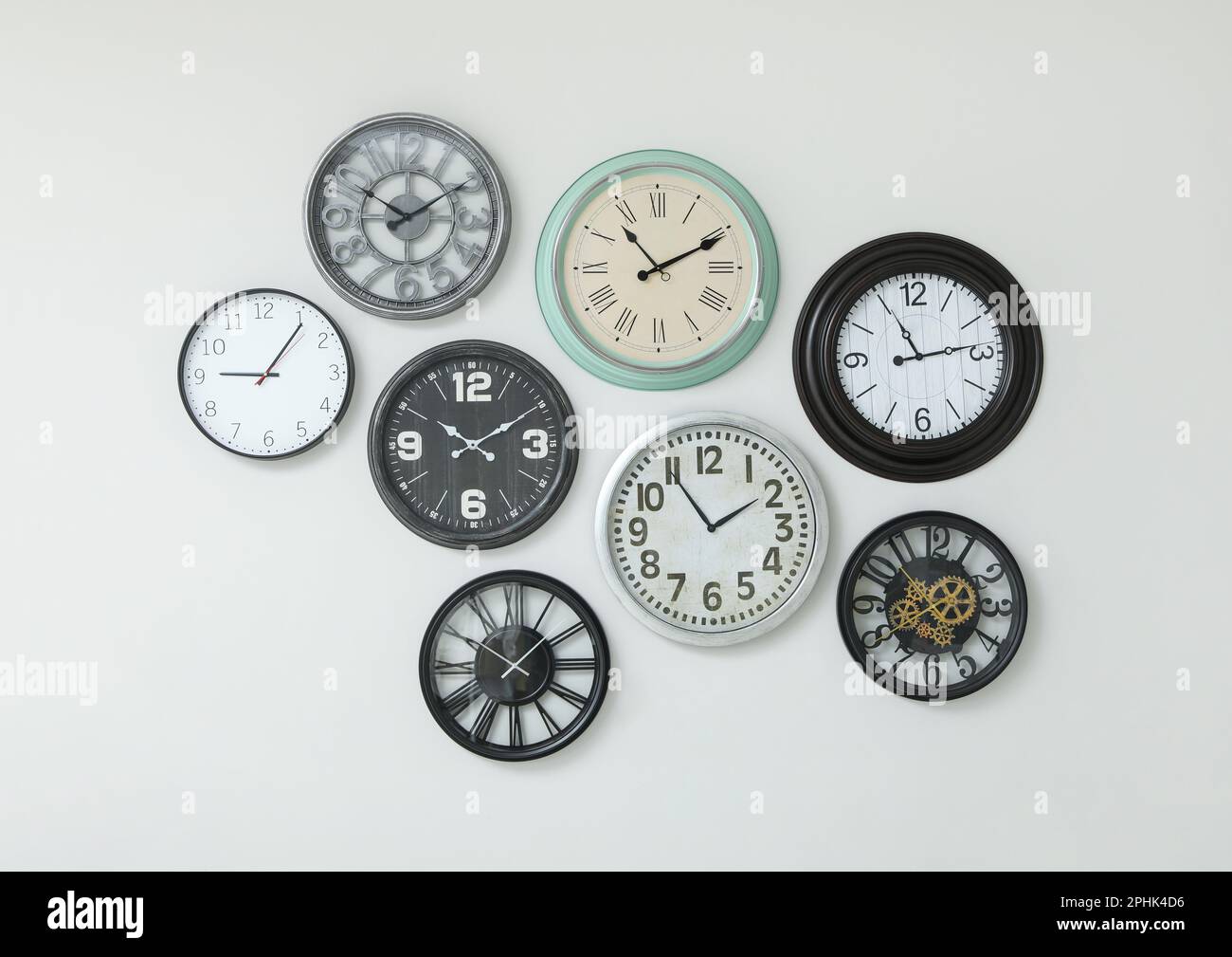Many different clocks hanging on white wall Stock Photo Alamy
