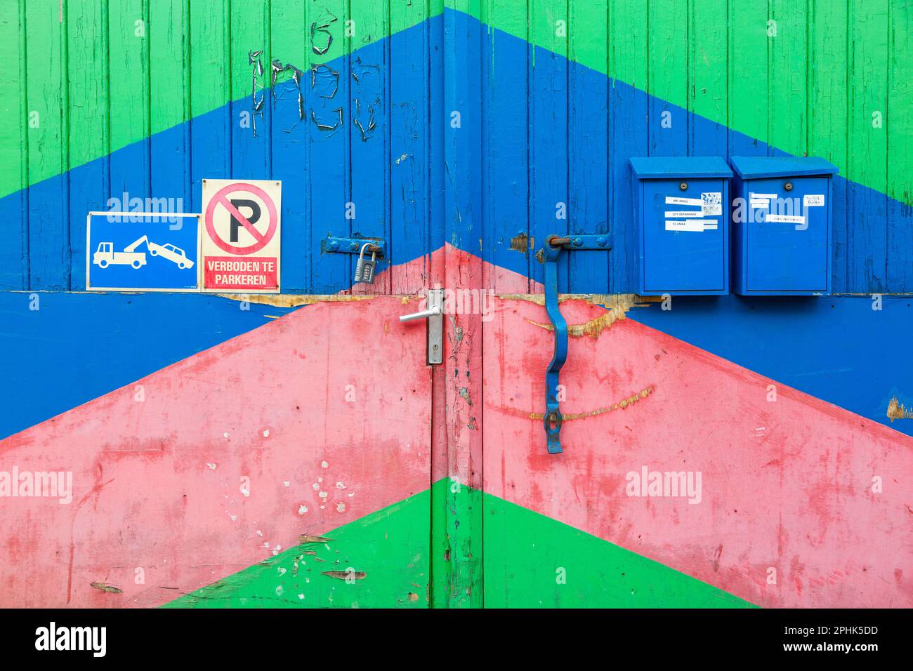 Garage door painted with wide oblique blue-green-red colored bands. Mail boxes. Brussels. Stock Photo