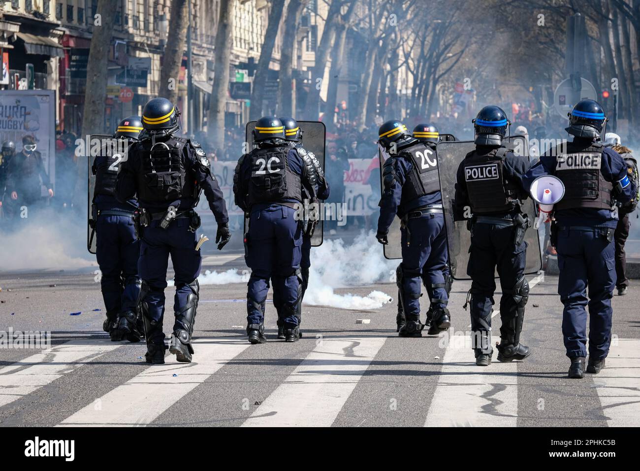 France, Lyon, 2023-03-28. Police officers from behind protecting themselves from demonstrators after tear gas was fired during the 10th demonstration Stock Photo