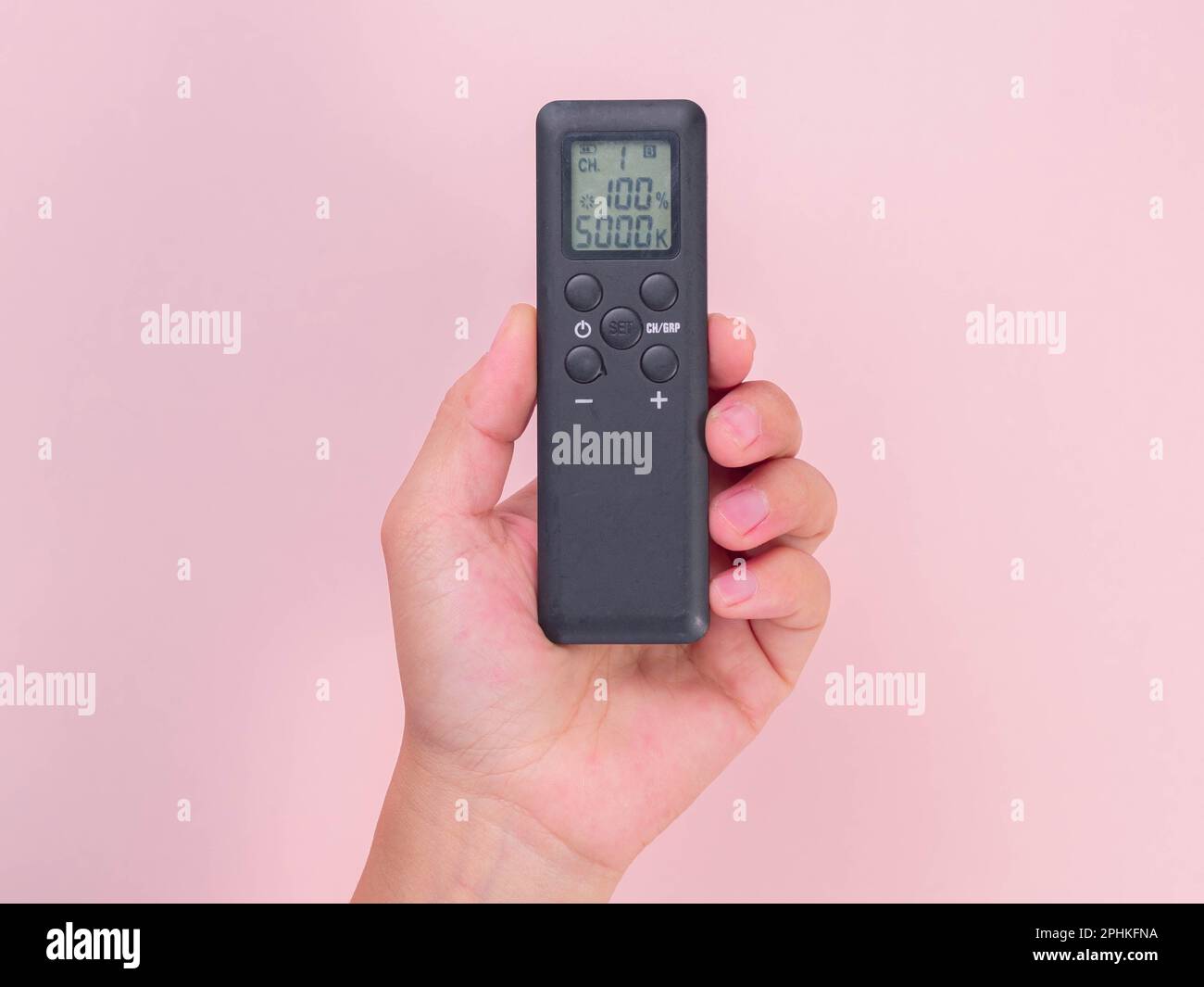 Hand holding remote control isolated on pink background. Remote control