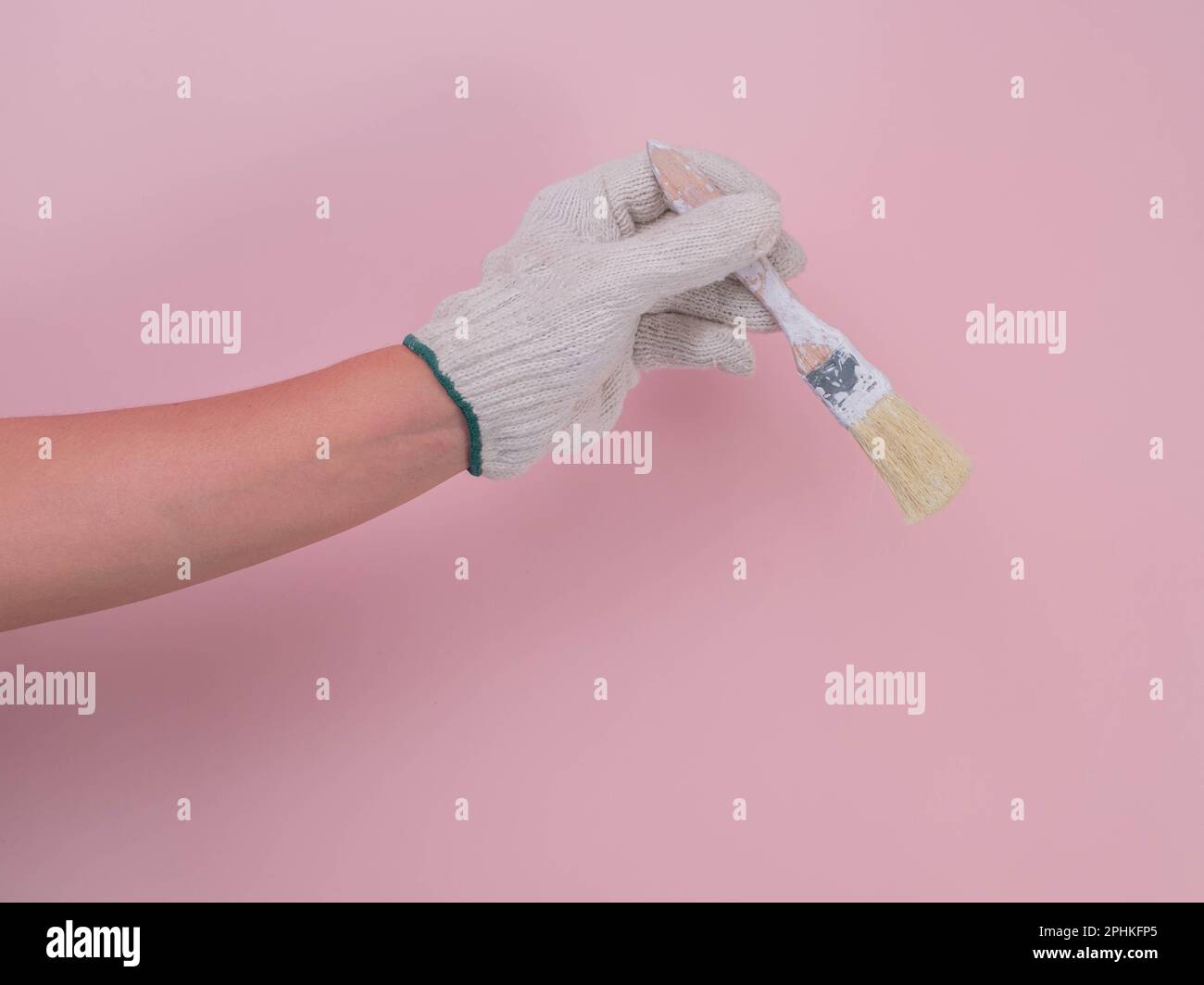 Hand in white knitted glove holding paint brush isolated on pink ...