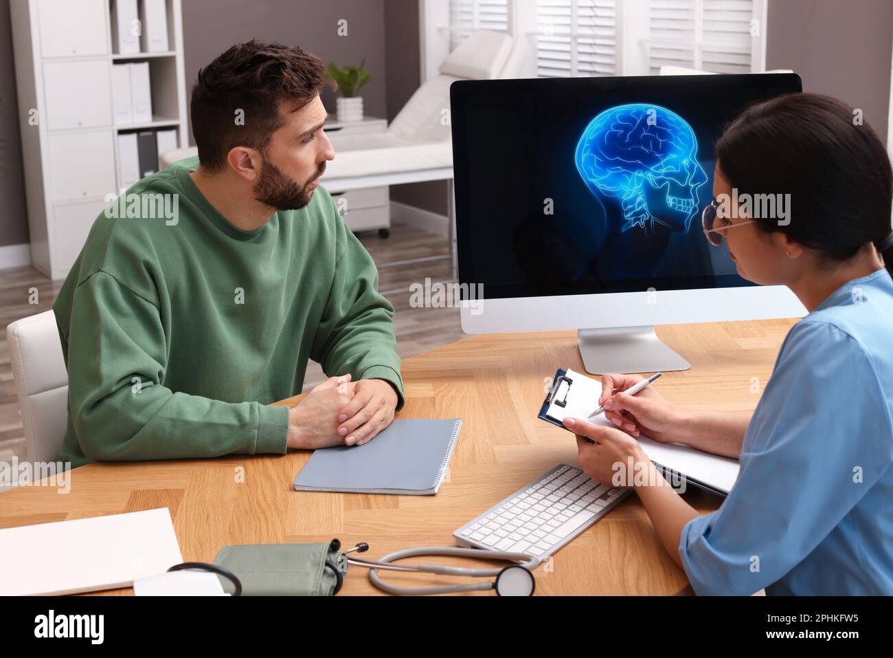 Neurologist consulting patient at table in clinic Stock Photo