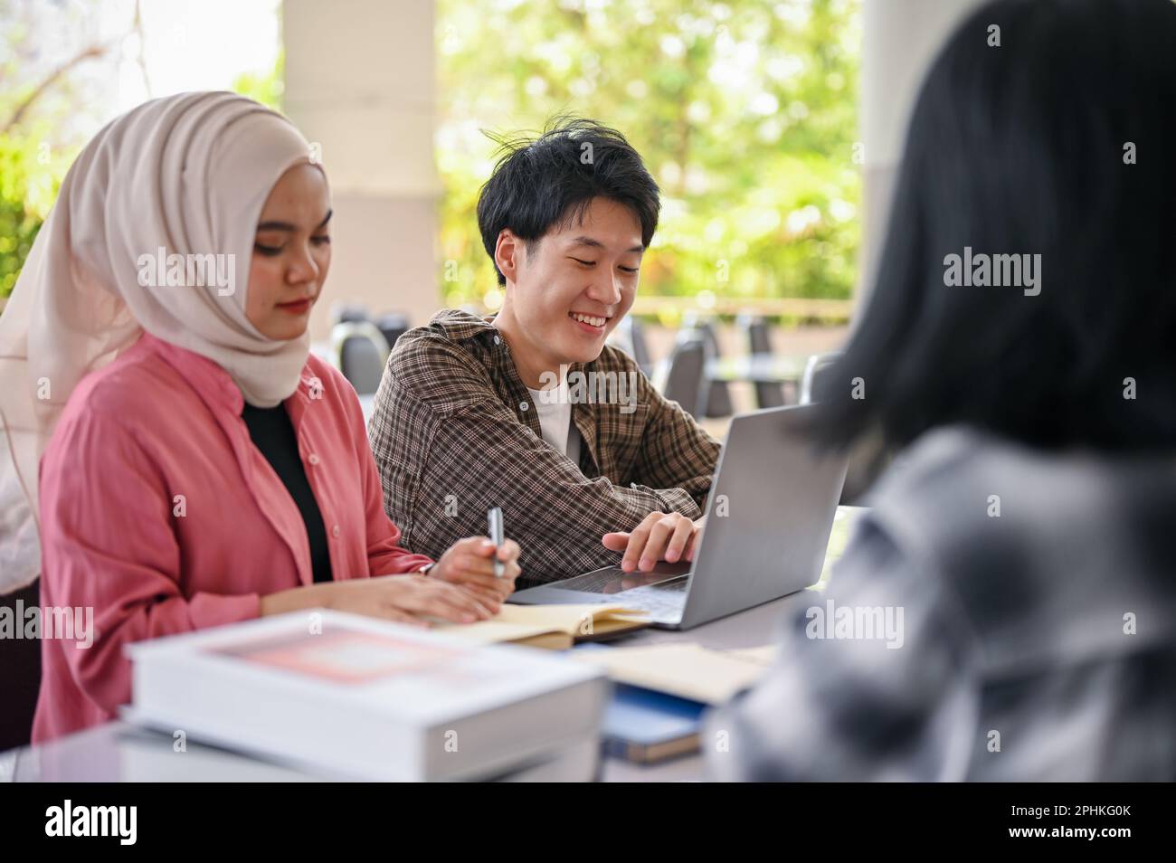 Happy young Asian male college student talking and working on a group ...