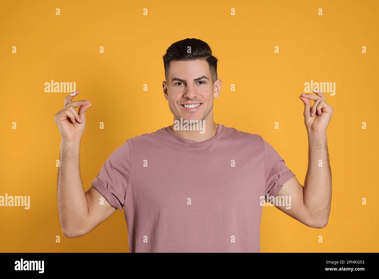 Handsome man snapping fingers on yellow background Stock Photo
