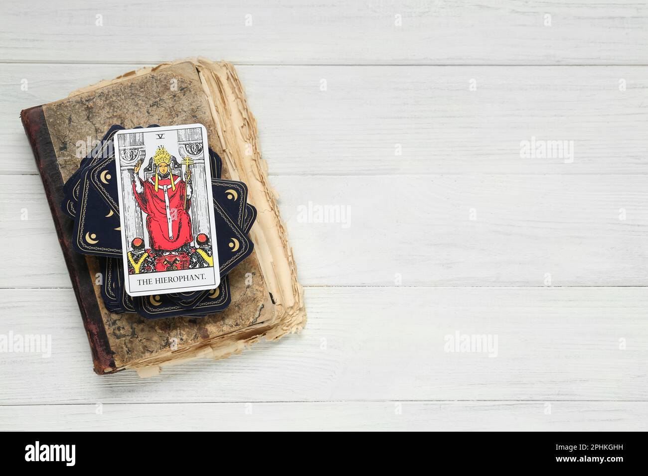 The Hierophant and other tarot cards with old book on white wooden table, top view. Space for text Stock Photo