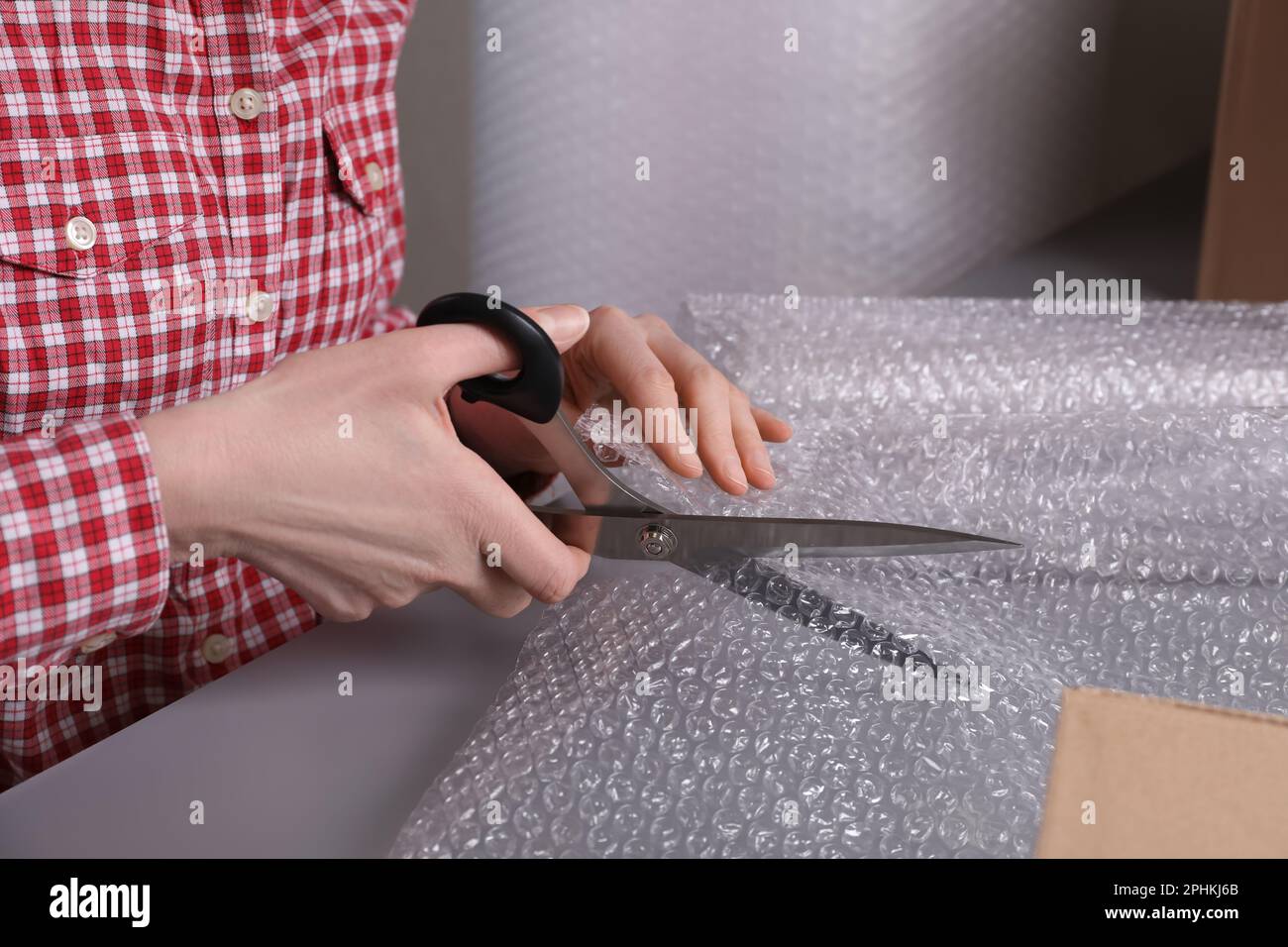 Woman cutting bubble wrap at table in warehouse, closeup Stock Photo Alamy