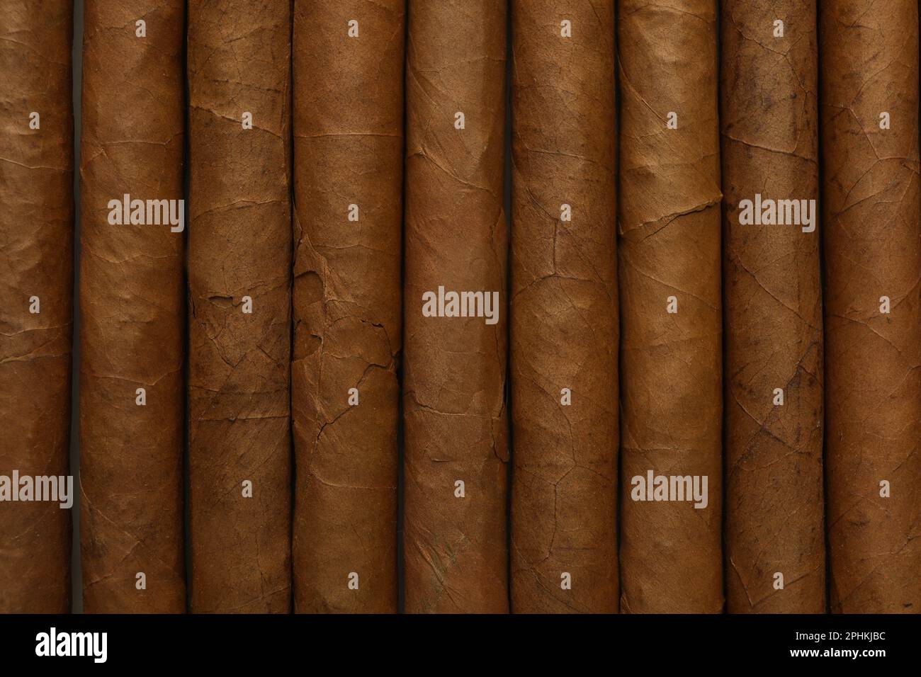 Many cigars wrapped in tobacco leaves as background, top view Stock