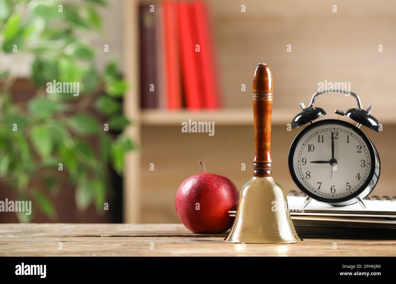 Golden school bell, apple, alarm clock and notebooks on wooden table in ...
