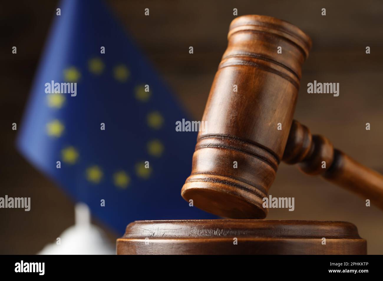 Closeup view of wooden judge's gavel and European Union flag on blurred ...