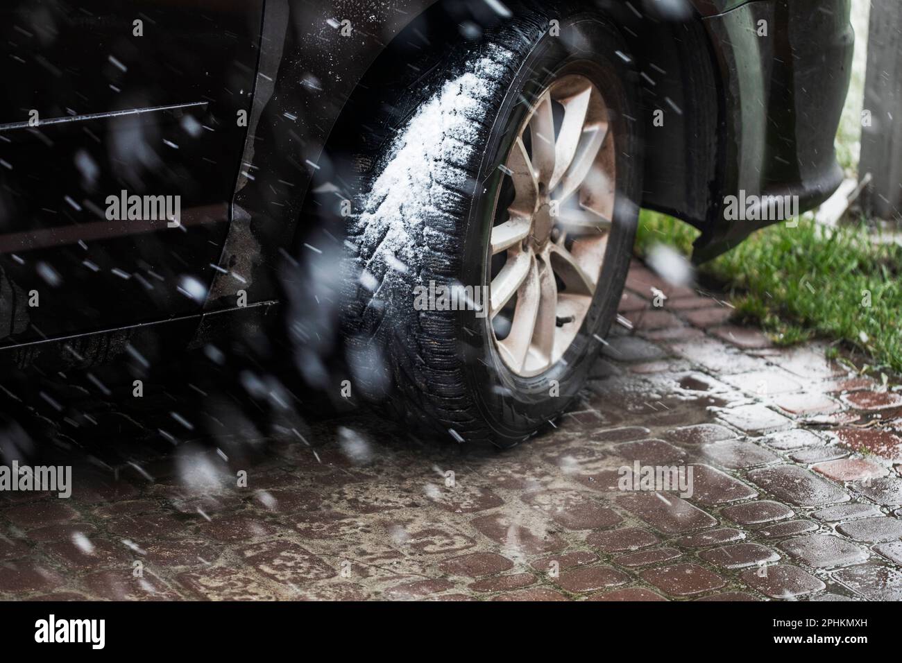 car wheel in winter tires in bad weather with snow when the grass turns